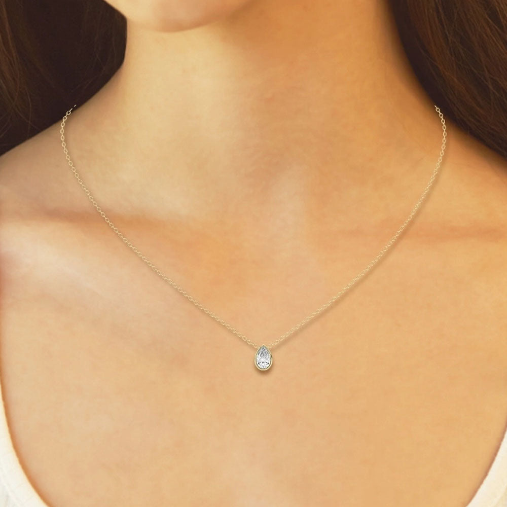 Front view of Puro Pear Bezel Diamond Pendant with yellow gold chain on model.
